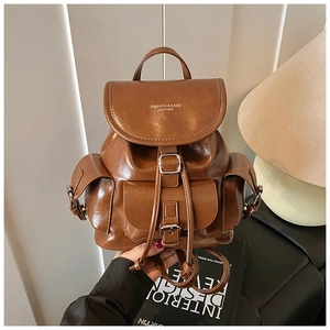 Detail of dark brown vintage faux leather backpack with metallic buckles and drawstring pockets