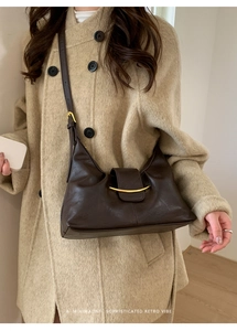 Gros plan d'un sac sous le bras marron avec boucle dorée sur un manteau en tweed