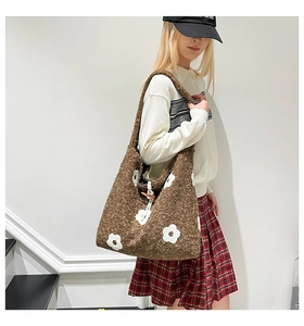 Close-up of brown wool shoulder bag featuring white floral patterns and toggle closure