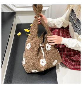 Close-up of brown wool shoulder bag with white flower pattern and drawstring closure