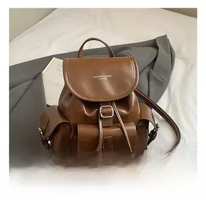 Detail view of a brown faux leather backpack with silver buckles in a lifestyle setting
