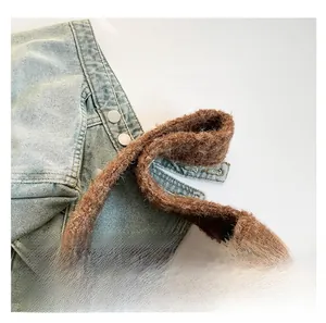 Detail of blue denim shoulder bag featuring a soft brown plush handle and silver buckle