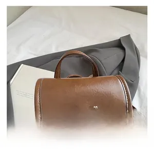 Detail of a brown leather backpack handle with embossed text and soft lighting