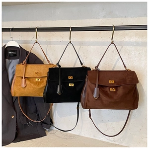 Detailed view of suede shoulder bags with golden twist-lock buckles in three colors