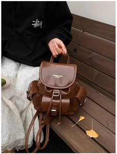 Detailed close-up of brown vintage leather backpack with buckles on wood bench