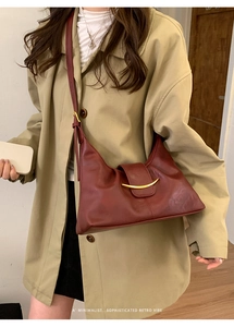 Détail du sac sous le bras bordeaux avec garniture métallique dorée minimaliste et style rétro