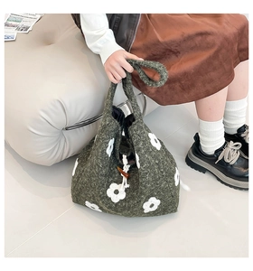 Detail of green knit bucket bag with white 3D flowers and a vintage horn toggle closure