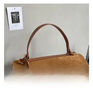 Detail of soft brown suede handbag featuring smooth leather handles and gold metal lock