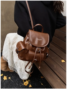 Detailed close-up of dark brown PU leather backpack with vintage clasp and side pockets