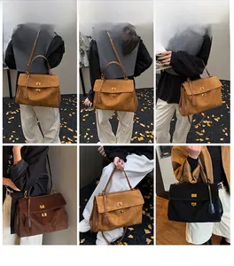 Detail of suede tote bag showing gold lock closure and large capacity shoulder strap use