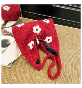 Red plush tote bag featuring white floral embroidery and a classic horn button closure