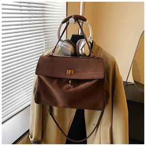 Detail view of large dark brown suede tote bag featuring vintage gold twist lock closures