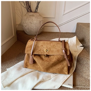 Close-up of caramel suede handbag with vintage gold metal buckle and textured finish