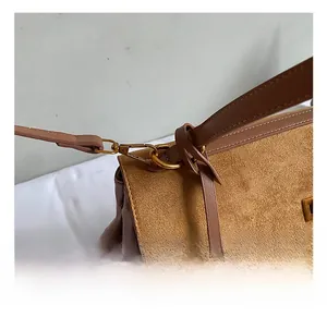 Detail of high-quality golden metal hook and brown suede texture on the shoulder bag