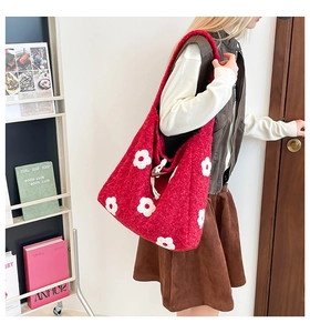 Detail of red plush tote bag with white flower patterns and wooden toggle button closure