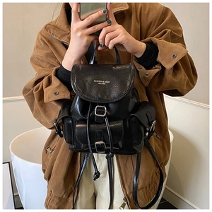 Close-up of black leather backpack with drawstring closure and silver metal buckles