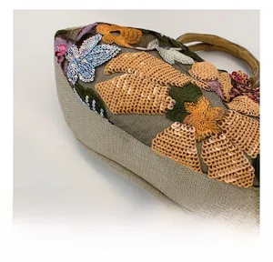 Detailed view of floral embroidery with sequins and natural bamboo handle on a retro tote