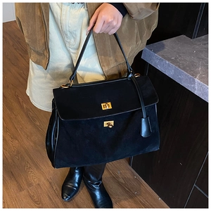 Detail of vintage gold double twist locks on a black suede and leather tote bag