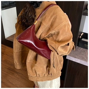 Détail du sac en cuir verni bordeaux avec finition brillante et ferrures dorées