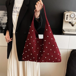 Détail du sac hobo en daim bordeaux avec rivets argentés et poignée minimaliste