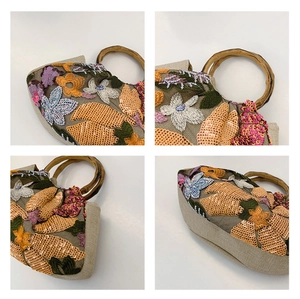Detail view of colorful floral sequin embroidery and natural bamboo handle on woven bag