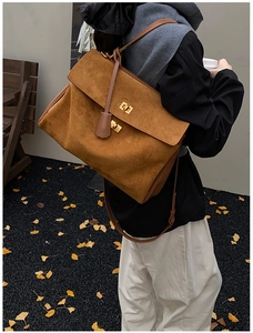 Close-up of brown suede oversized shoulder bag with double golden twist-lock buckles