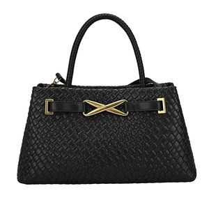 Sac à main tissé noir minimaliste avec une boucle en métal doré en forme de X sur fond blanc