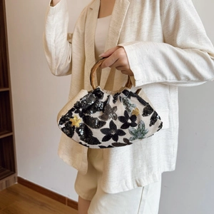 Close-up of ethnic hand-woven bag featuring floral sequin embroidery and a bamboo handle