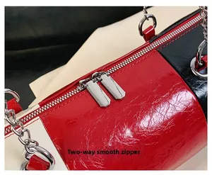 Close-up of smooth two-way zippers and glossy cracked leather on the cylinder bag
