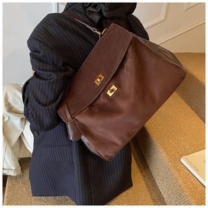 Detail of a brown large suede shoulder bag featuring two gold buckles and leather straps