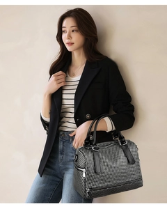 Close-up of black and white checkered tote bag with leather handles and silver hardware