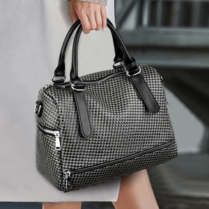 Detail of houndstooth Boston bag with black leather handles and silver hardware
