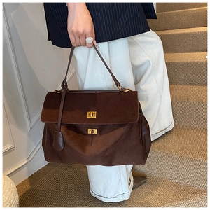Close-up of dark brown suede tote bag featuring dual golden twist-lock closures and texture