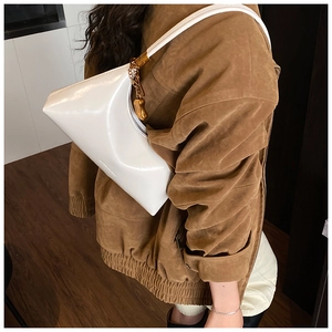 Détail du sac croissant en cuir verni blanc avec panneaux géométriques et chaîne dorée