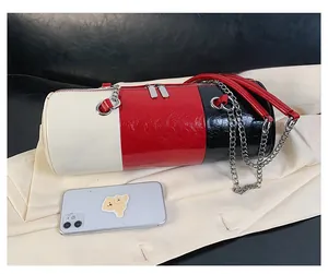 Detailed view of tricolor cylinder bag with patent finish and silver chain strap