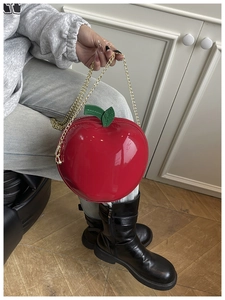 Detailed macro view of the glossy red apple-shaped purse with green leaf accent and gold chain