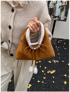 Detail of plush brown suede handbag featuring white faux shearling trim and bow accents