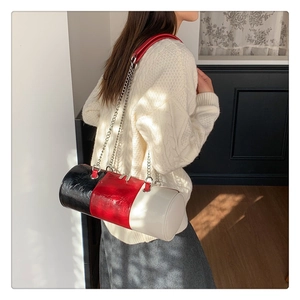 Detail of tricolor cylindrical bag featuring shiny wrinkled leather and silver chain strap