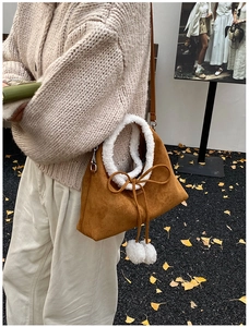 Detail of plush brown suede bag with soft white faux shearling handle and pompom drawstring