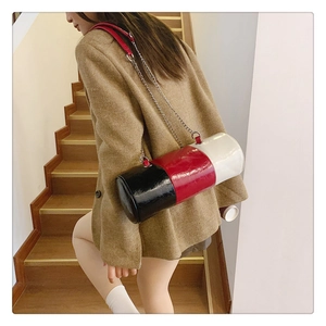Three-color拼接 cylinder bag with silver metal chain strap shown in a real-life side view