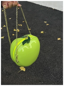 Detail of creative green apple-shaped chain bag in shiny patent leather texture