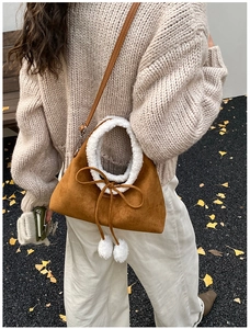 Close-up of brown suede handbag with white faux fur trim styled in autumn outdoor setting