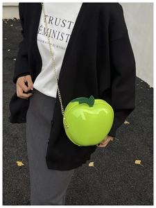 Close-up of apple-shaped crossbody bag in neon green with gold chain and leaf detail
