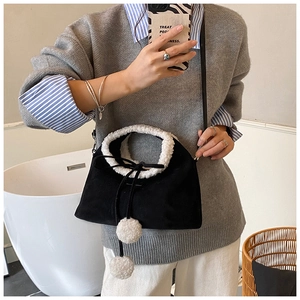 Detail of a plush drawstring bucket bag featuring white lamb wool trim and soft pom-poms