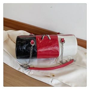 Detail of glossy pleated patent leather cylinder bag with silver chain and tri-color design