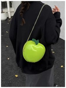Detailed close-up of a creative apple-shaped bright green glossy crossbody bag with gold chain