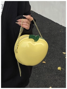 Detailed close-up of yellow apple-shaped chain bag with green leaf accent and gold strap