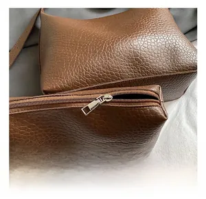 Détail du cuir marron texture litchi avec fermeture éclair argentée sur le sac