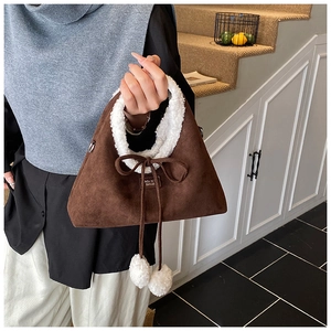 Close-up of caramel plush handbag with white faux shearling trim and cute pom poms