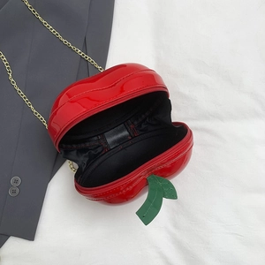 Detail view of the red apple-shaped bag showing gold chain and black fabric lining